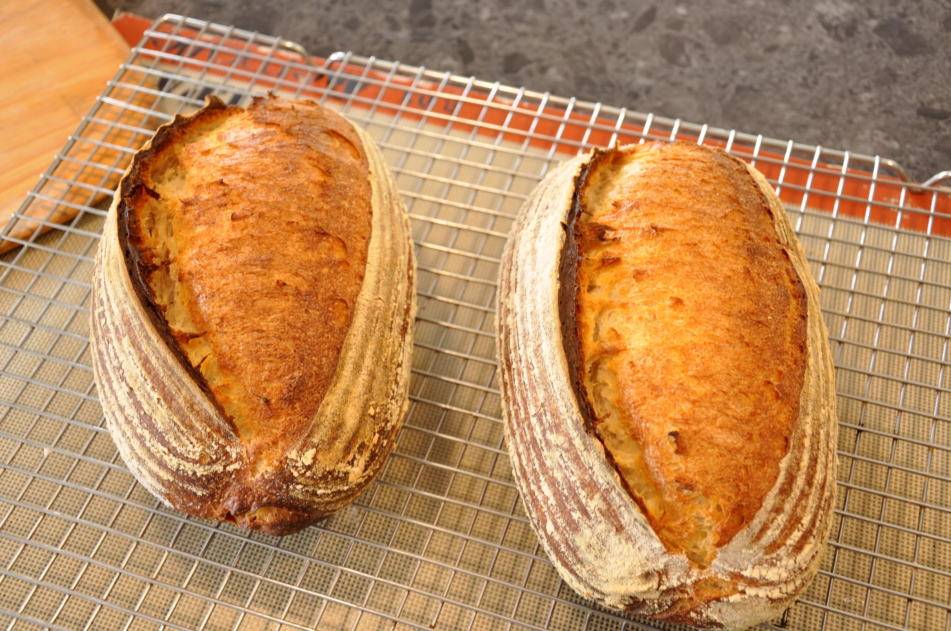 Two loaves of bread on a cooling rack

AI-generated content may be incorrect.