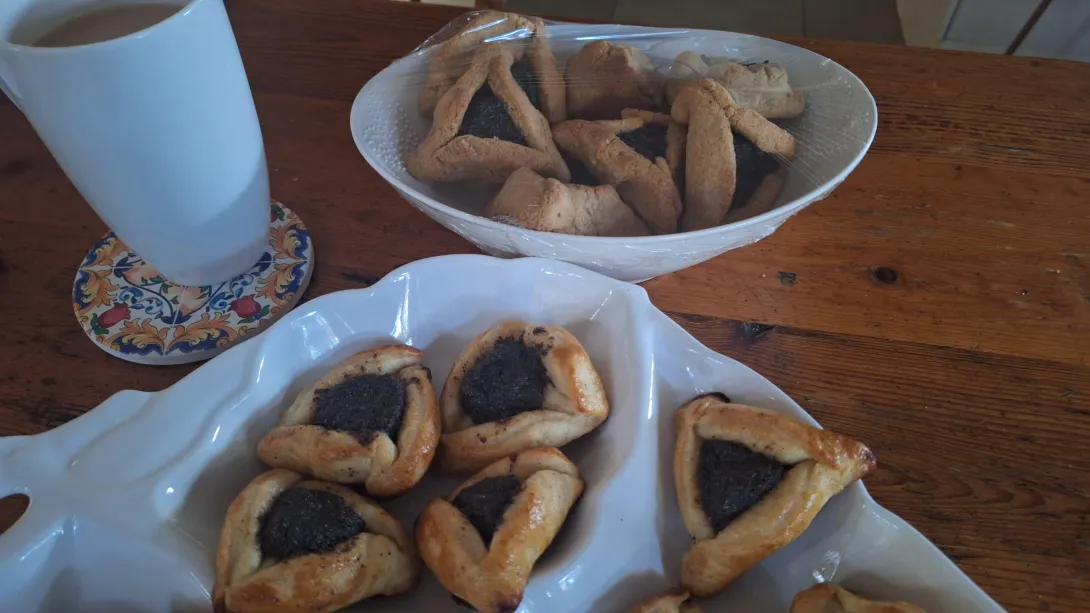 Plates of hamantaschen. Thicker looking gluten-free ones at the back and smaller yeasted ones in front